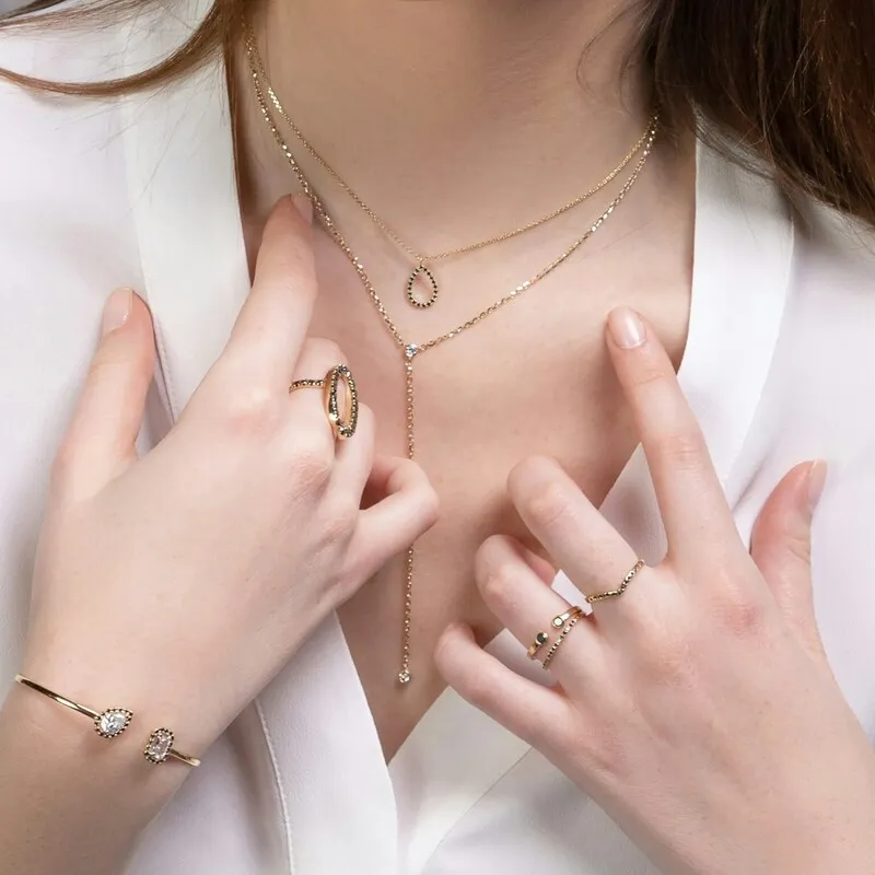 A person in white wearing multiple gold jewelry pieces