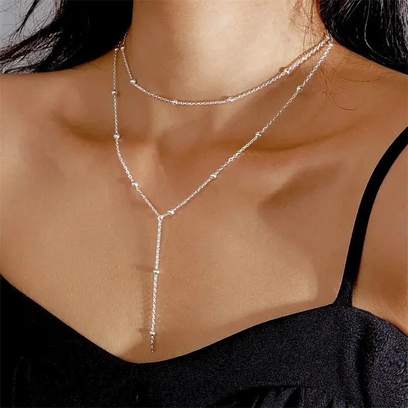 A double layer silver necklace worn by someone in a black top